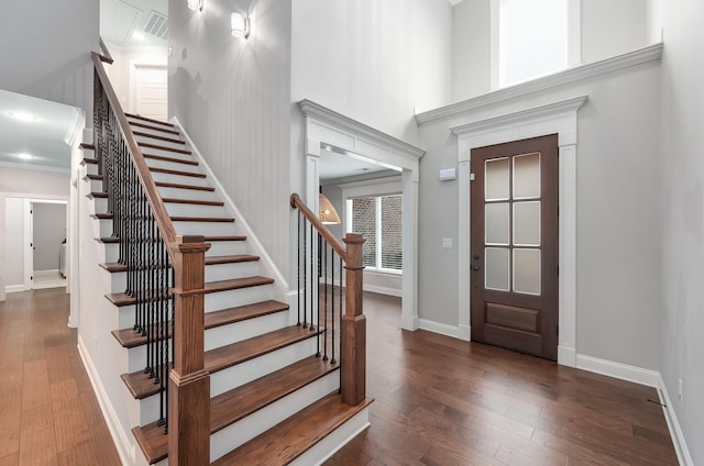 foyer entrance with a towering ceiling and dark hardwood / wood-style floors