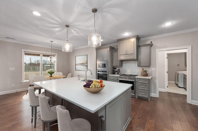 kitchen featuring decorative light fixtures, gray cabinets, decorative backsplash, and appliances with stainless steel finishes