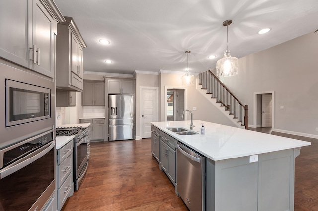 kitchen featuring sink, a kitchen island with sink, hanging light fixtures, gray cabinetry, and stainless steel appliances