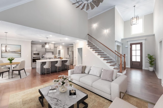 living room with a high ceiling, crown molding, dark hardwood / wood-style floors, and an inviting chandelier