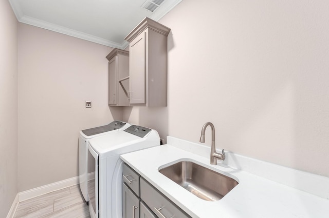 washroom with cabinets, crown molding, washer and dryer, and sink