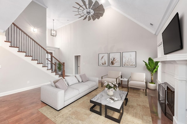 living room featuring an inviting chandelier, ornamental molding, hardwood / wood-style floors, and high vaulted ceiling