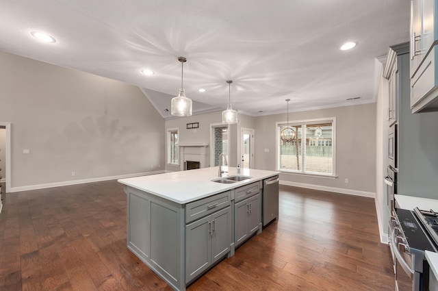 kitchen with hanging light fixtures, gray cabinets, stainless steel appliances, and an island with sink