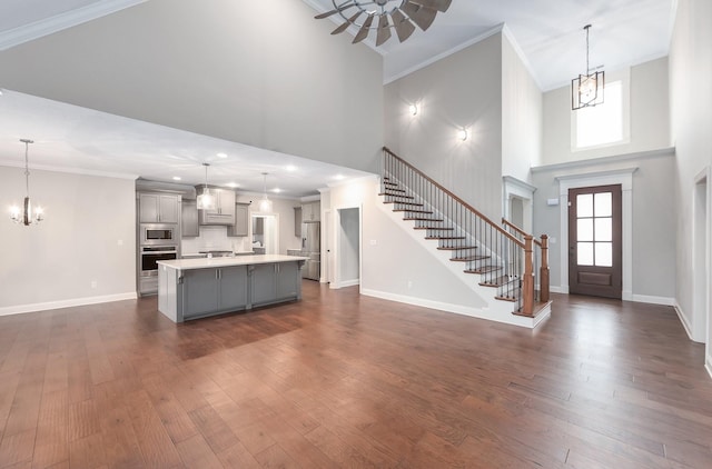 foyer entrance with a towering ceiling, ornamental molding, dark hardwood / wood-style floors, and a chandelier