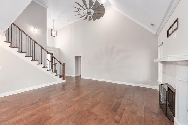 unfurnished living room with crown molding, an inviting chandelier, dark hardwood / wood-style floors, and high vaulted ceiling