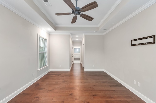 empty room featuring ceiling fan, crown molding, dark hardwood / wood-style flooring, and a tray ceiling