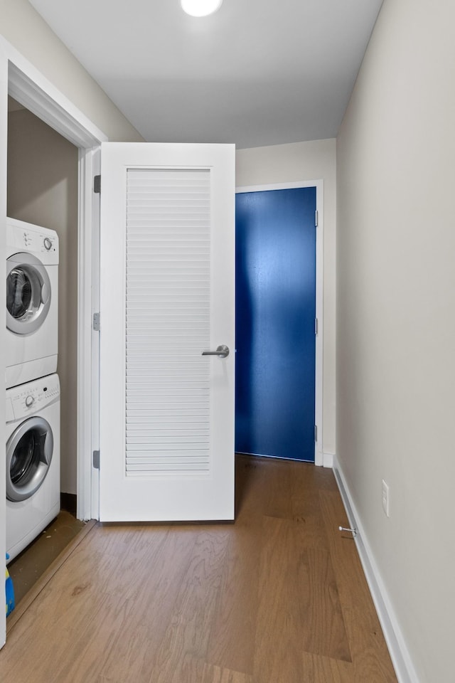 laundry room with hardwood / wood-style floors and stacked washer and clothes dryer