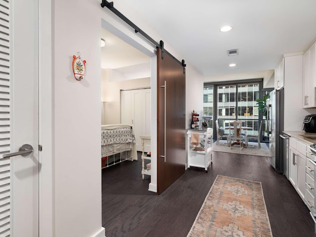 corridor with a barn door and dark hardwood / wood-style floors