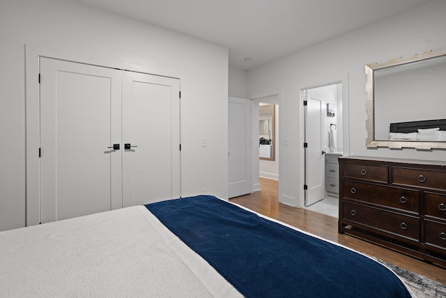 bedroom featuring a closet, ensuite bath, and hardwood / wood-style flooring