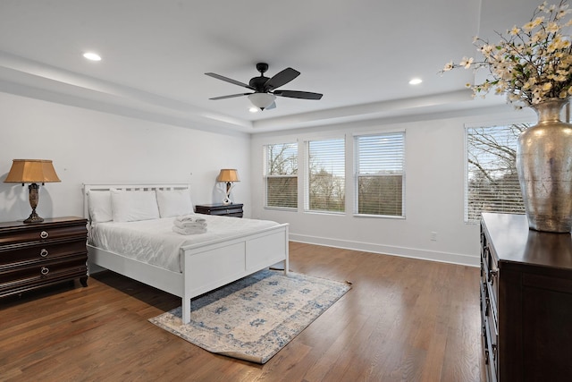 bedroom with a raised ceiling, ceiling fan, and dark hardwood / wood-style floors