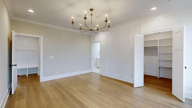 interior space with a chandelier, light wood-type flooring, ornamental molding, and a closet