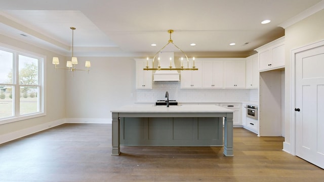 kitchen with a kitchen island with sink, sink, a chandelier, and decorative light fixtures