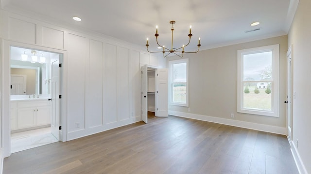 unfurnished dining area with plenty of natural light, crown molding, and a chandelier