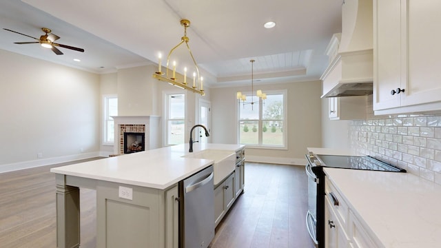 kitchen featuring white cabinets, pendant lighting, stainless steel appliances, and a kitchen island with sink