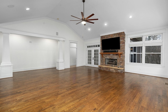 unfurnished living room featuring lofted ceiling, french doors, a stone fireplace, ceiling fan, and dark hardwood / wood-style floors