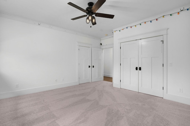 unfurnished bedroom with ceiling fan, light colored carpet, crown molding, and a closet