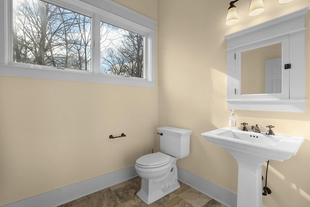 bathroom with toilet, sink, and a wealth of natural light