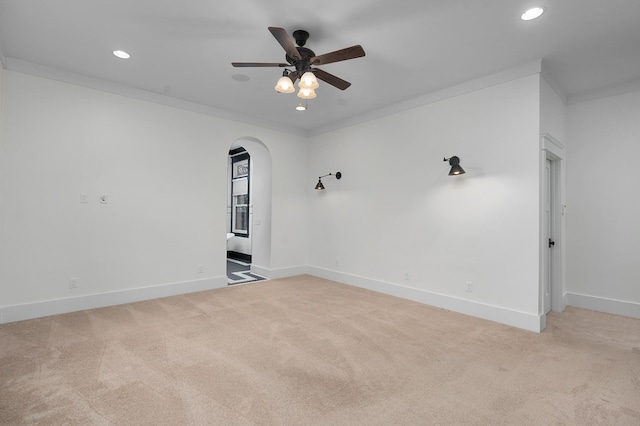 unfurnished room with ceiling fan, light colored carpet, and ornamental molding