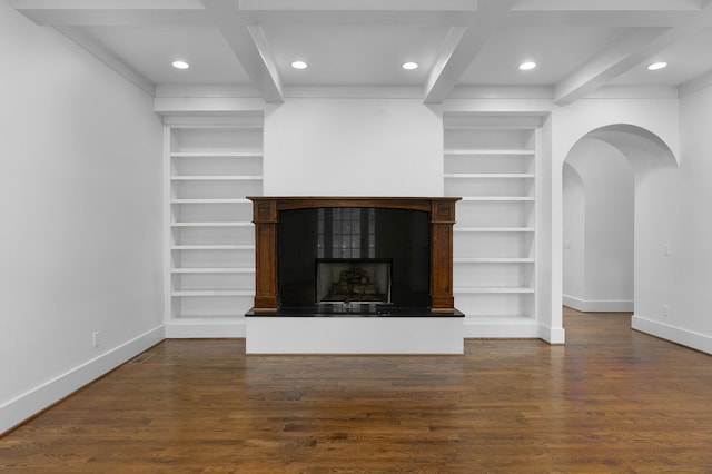 unfurnished living room featuring built in shelves, beamed ceiling, dark wood-type flooring, and coffered ceiling