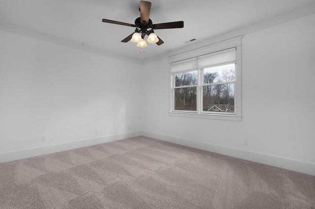 carpeted spare room featuring crown molding and ceiling fan