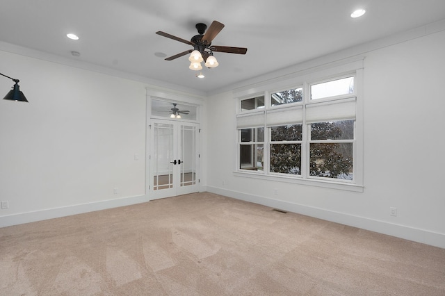 carpeted empty room with ceiling fan, crown molding, and french doors