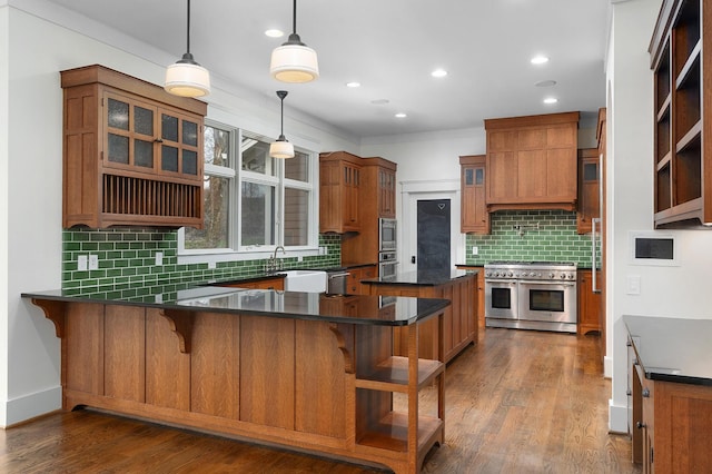 kitchen with a kitchen bar, kitchen peninsula, dark hardwood / wood-style flooring, stainless steel appliances, and decorative light fixtures