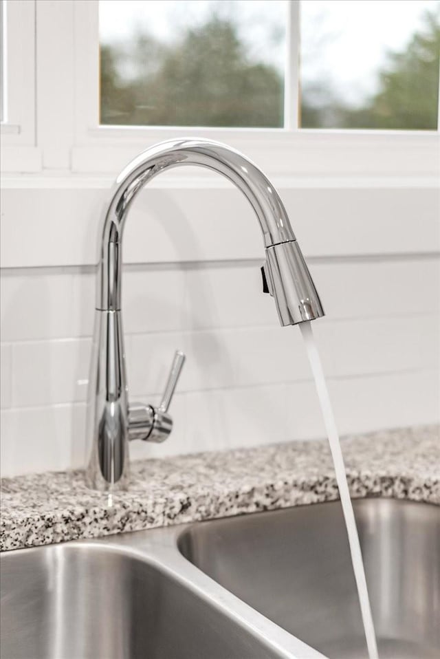 details with light stone countertops, white cabinetry, and sink