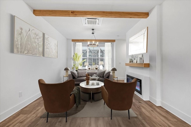 sitting room with beam ceiling and wood-type flooring