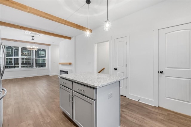 kitchen with beamed ceiling, pendant lighting, light hardwood / wood-style floors, gray cabinets, and a kitchen island