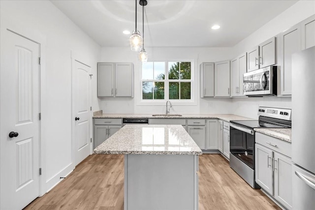 kitchen featuring gray cabinetry, a center island, hanging light fixtures, sink, and appliances with stainless steel finishes