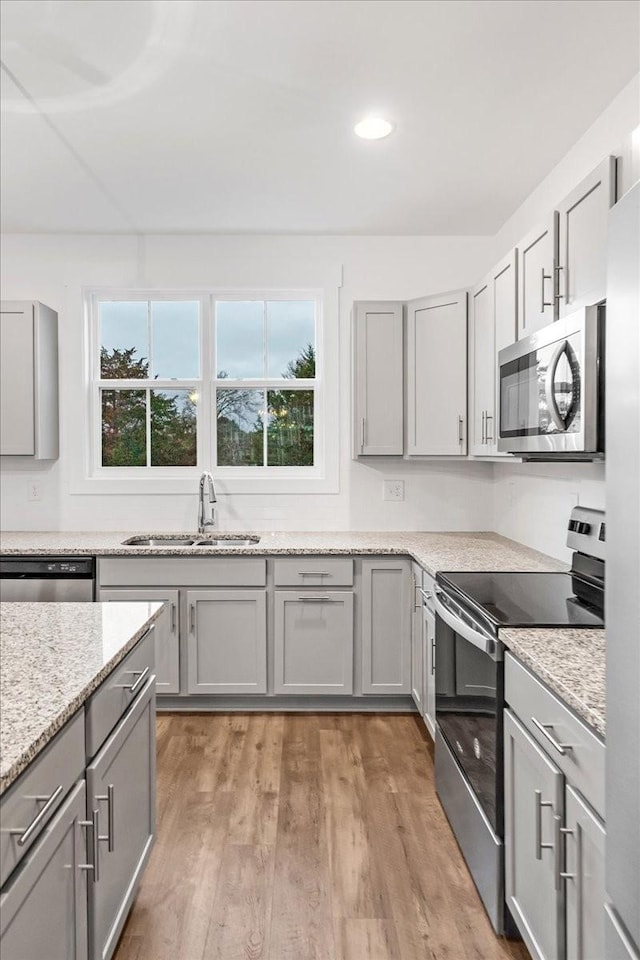 kitchen with gray cabinetry, sink, light hardwood / wood-style flooring, and appliances with stainless steel finishes