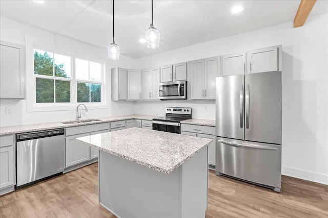 kitchen featuring gray cabinetry, a center island, sink, appliances with stainless steel finishes, and decorative light fixtures