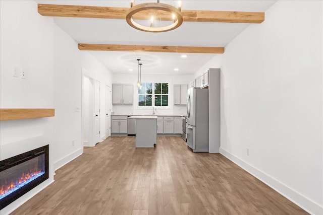 kitchen featuring gray cabinetry, stainless steel appliances, beam ceiling, a kitchen island, and hanging light fixtures