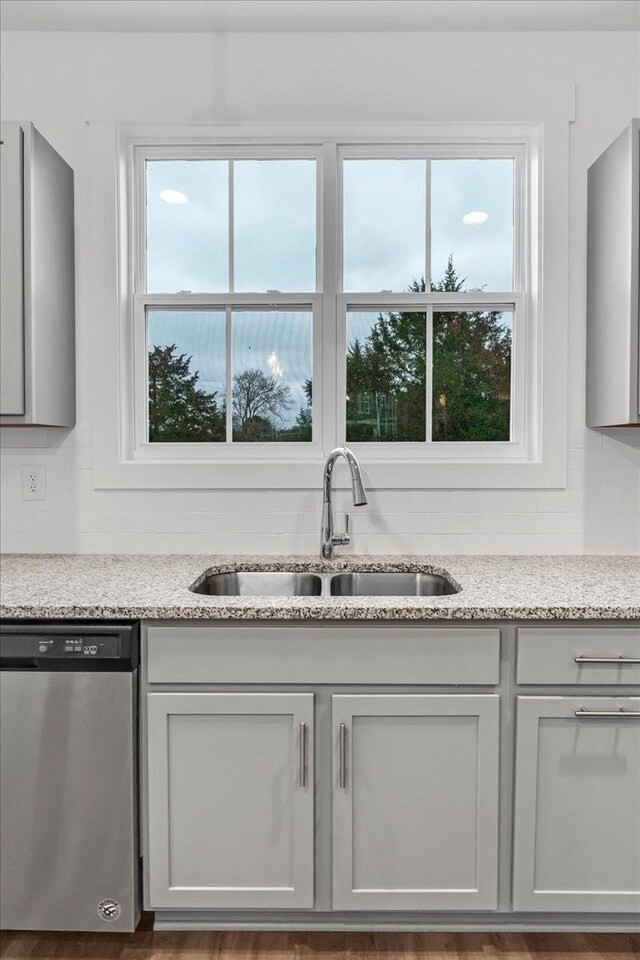 room details with light stone counters, dishwasher, and sink