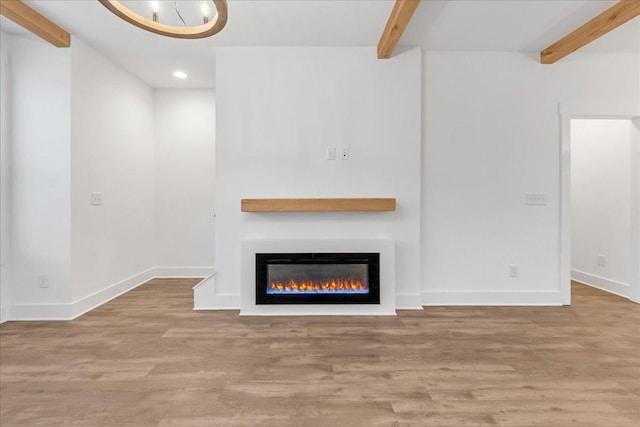 unfurnished living room featuring beamed ceiling and light hardwood / wood-style floors