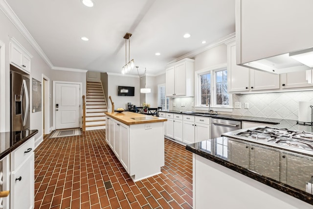 kitchen featuring wood counters, backsplash, stainless steel appliances, pendant lighting, and white cabinetry