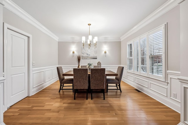 dining space featuring a chandelier, hardwood / wood-style flooring, and ornamental molding