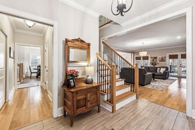 stairs featuring crown molding, french doors, and a notable chandelier