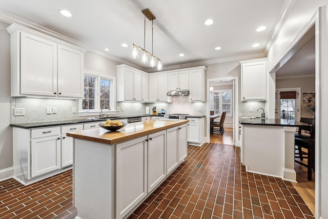 kitchen with decorative light fixtures, a kitchen island, white cabinetry, and wooden counters