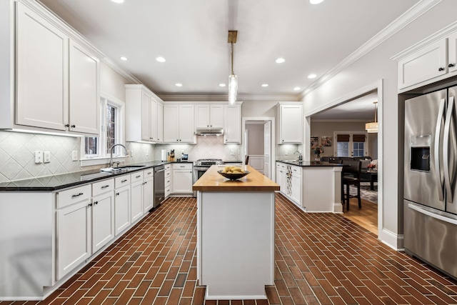 kitchen featuring sink, stainless steel appliances, a kitchen island, wooden counters, and white cabinets