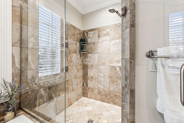 bathroom featuring plenty of natural light, a tile shower, and crown molding