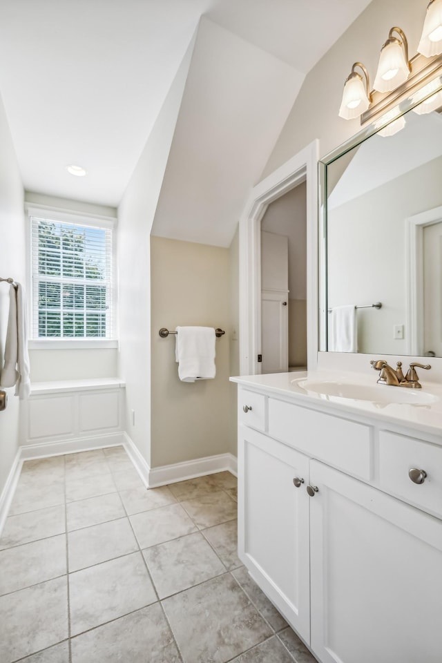 bathroom with tile patterned flooring, vanity, and vaulted ceiling