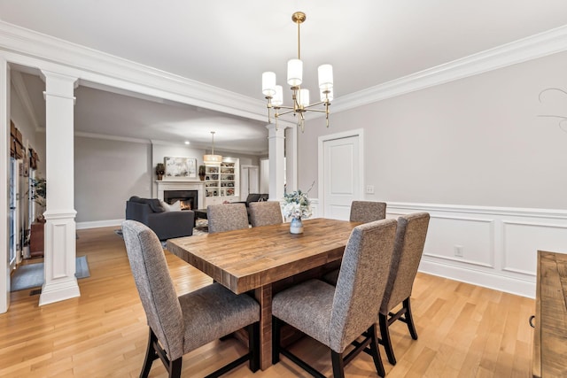 dining room with a chandelier, light wood-type flooring, ornate columns, and crown molding