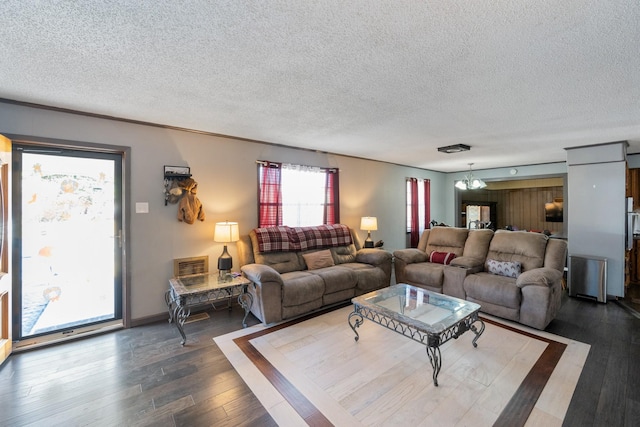 living room with dark wood-type flooring, a textured ceiling, and a notable chandelier