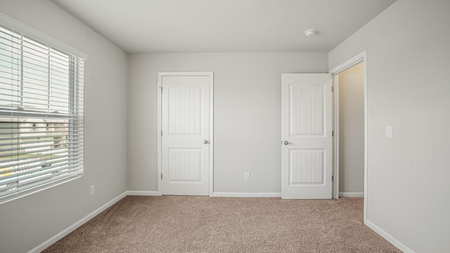 unfurnished bedroom with a closet, light colored carpet, and multiple windows