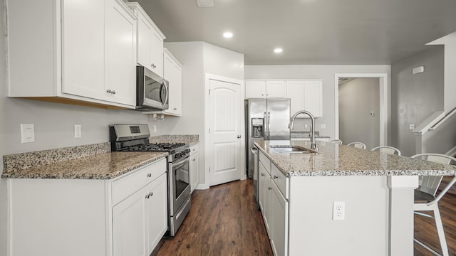 kitchen featuring a kitchen island with sink, sink, dark hardwood / wood-style flooring, white cabinetry, and stainless steel appliances