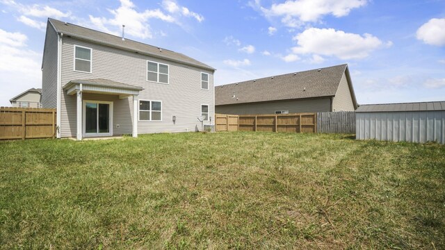 rear view of property featuring a storage shed and a lawn