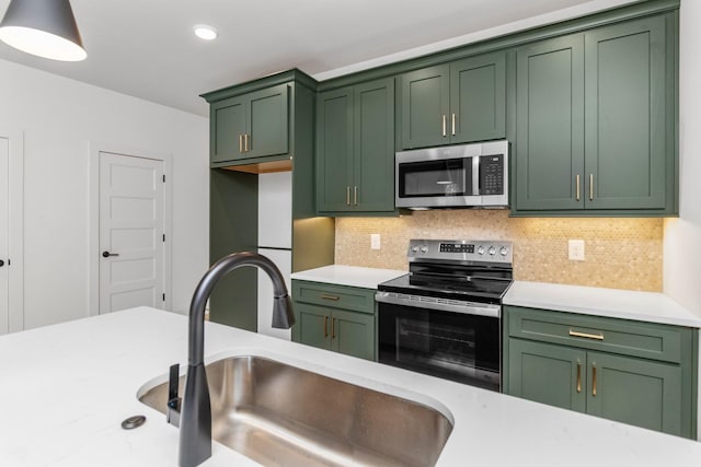 kitchen featuring decorative backsplash, appliances with stainless steel finishes, green cabinets, and sink