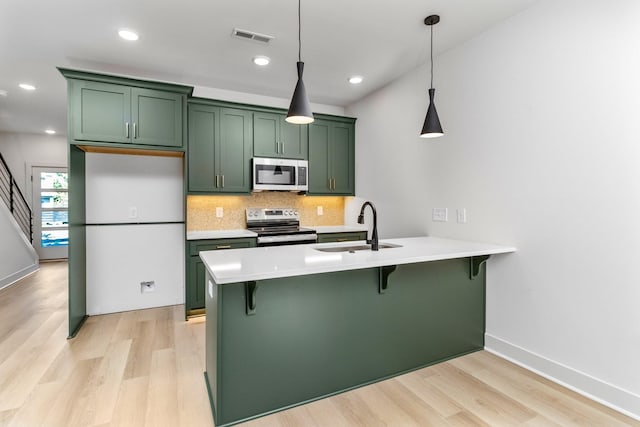 kitchen with appliances with stainless steel finishes, backsplash, sink, pendant lighting, and green cabinets