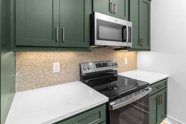 kitchen featuring appliances with stainless steel finishes, backsplash, and green cabinets